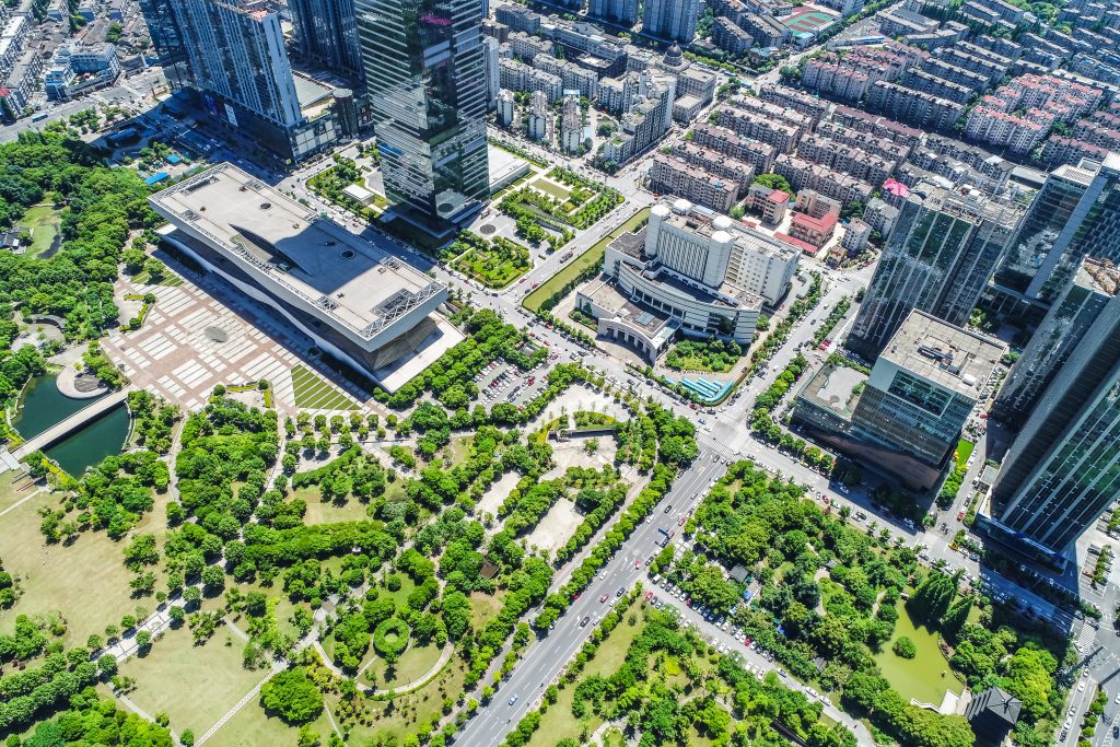Aerial view of modern urban real estate development with high-rise buildings, landscaped parks, and well-planned city infrastructure.